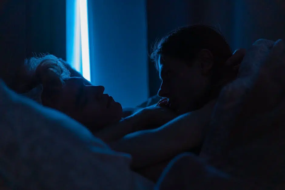Couple embracing in dimly lit room at night.