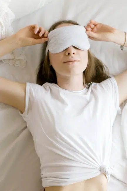 Relaxed woman wearing sleep mask in bed.